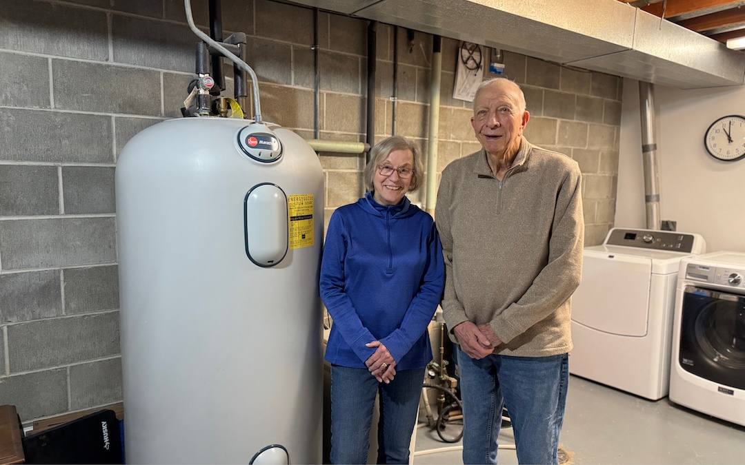 Meeker members standing next to water heater